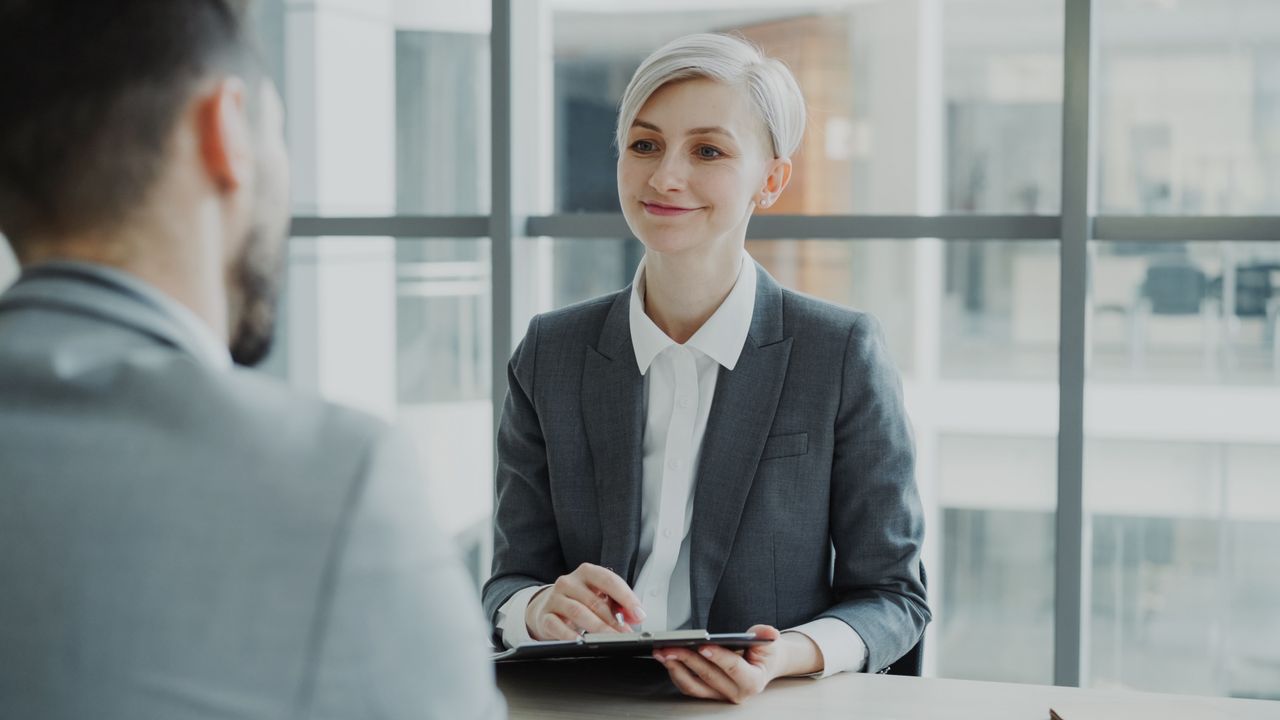 Mastering the First Impression: Your intriguing post title goes here Confident woman interviewing candidate in a modern office. Ideal for business and HR visuals.